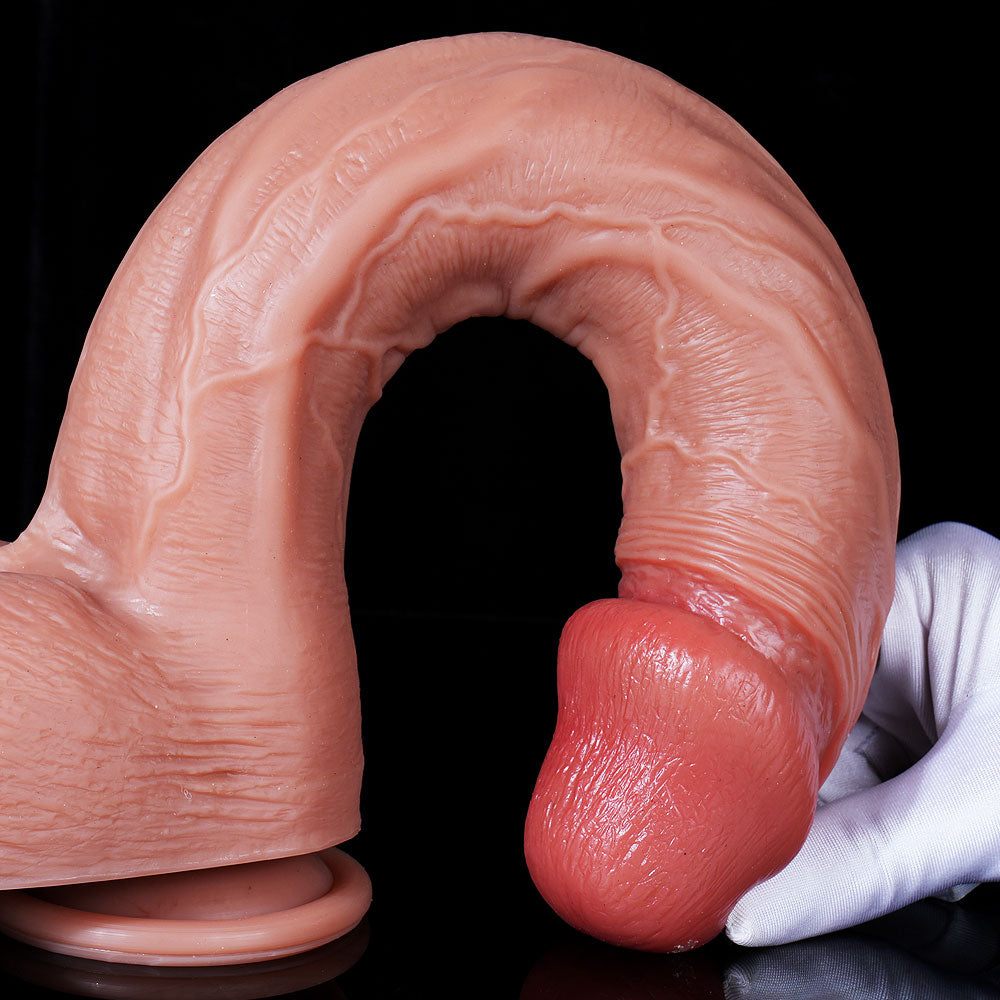 hand pressing down on crowned head of 14 inch dildo to demonstrate dual-layer flexibility